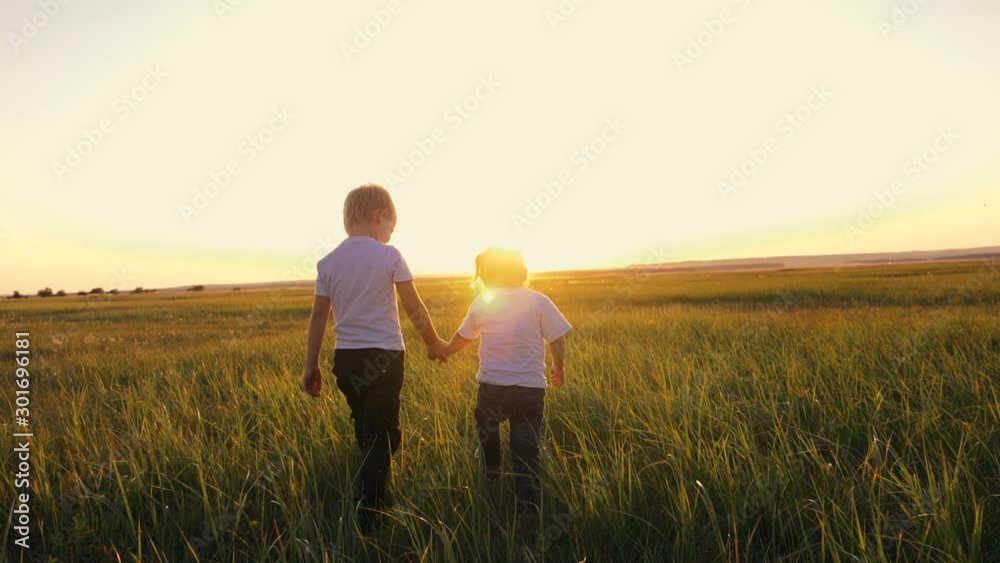 Children boy and girl walking on the green grass holding hands. Children boy and girl walking on the green grass holding hands.