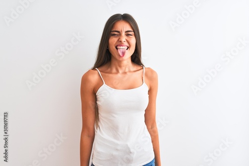 Young beautiful woman wearing casual t-shirt standing over isolated white background sticking tongue out happy with funny expression. Emotion concept.