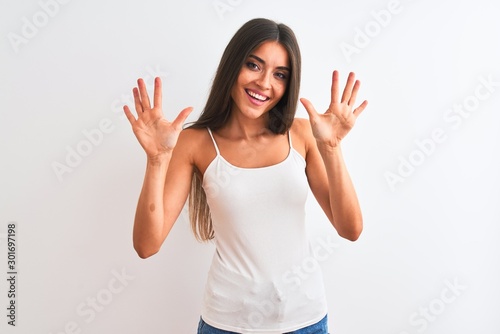 Young beautiful woman wearing casual t-shirt standing over isolated white background showing and pointing up with fingers number ten while smiling confident and happy.