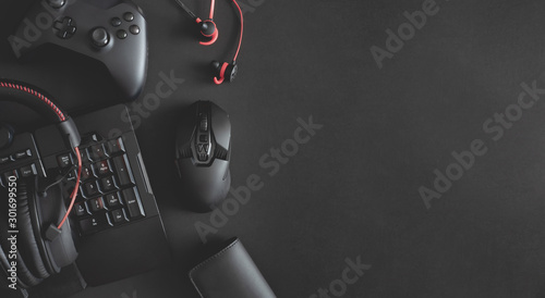 gamer work space concept, top view a gaming gear, mouse, keyboard, joystick, headset and in ear headphone on black table background. photo