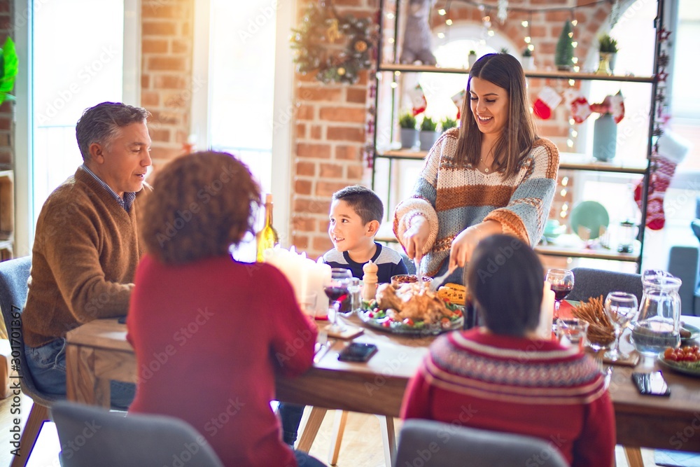 Beautiful family smiling happy and confident. One of them curving roasted turkey celebrating christmas at home Beautiful family smiling happy and confident. One of them curving roasted turkey celebrating christmas at home