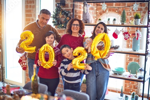 Beautiful family smiling happy and confident. Standing and posing holding 2020 balloons celebrating new year at home