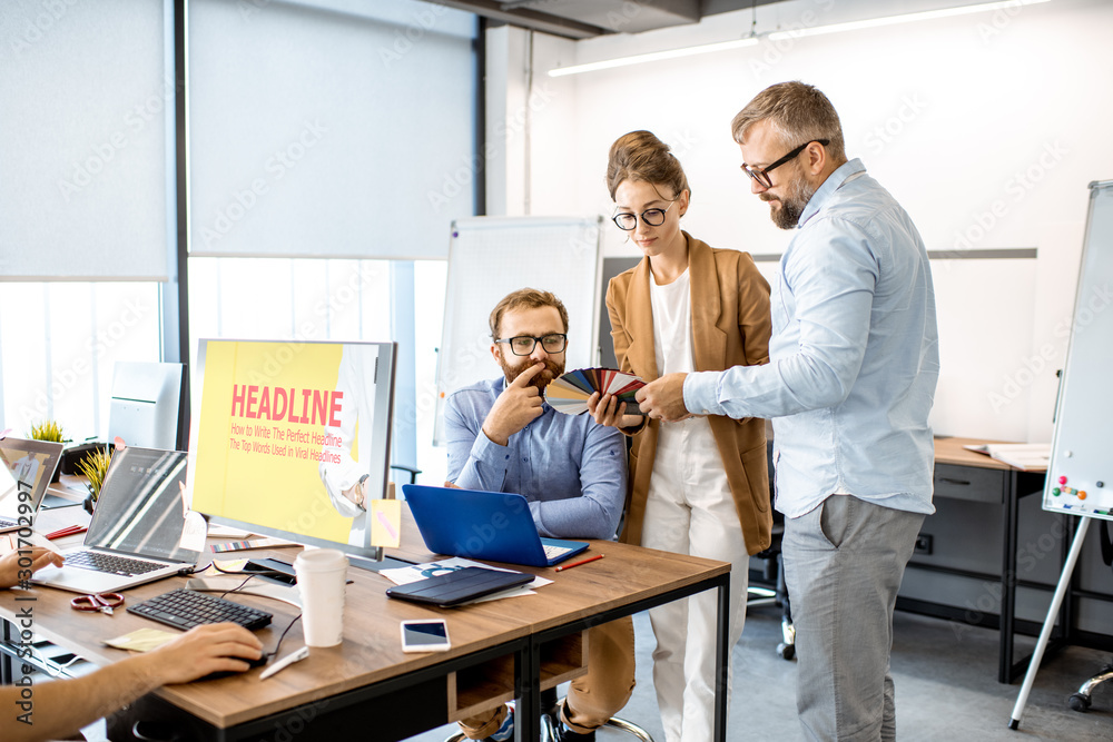 Group of diverse creative people having a small discussion, working as a web designers in the modern office or coworking space Group of diverse creative people having a small discussion, working as a web designers in the modern office or coworking space