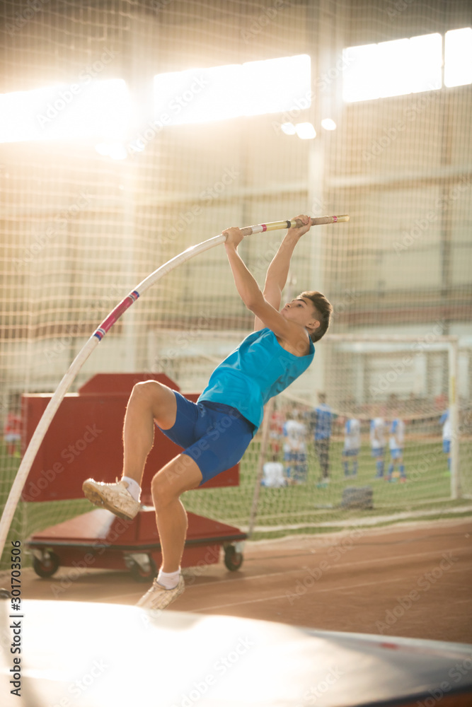 Obraz premium Pole vaulting - man is pushing the pole against the floor and starting his jump