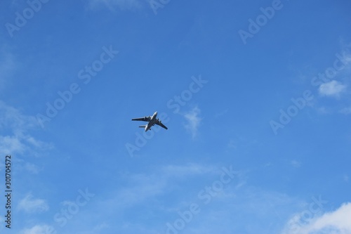 the plane flies away into the distance against the blue sky with white clouds. the dream of traveling to distant countries through the airspace by plane.