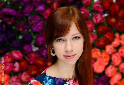Beauty concept. Close-up Portrait of a pretty red-haired student girl with long straight hair on a colored background in a multi-colored dress.