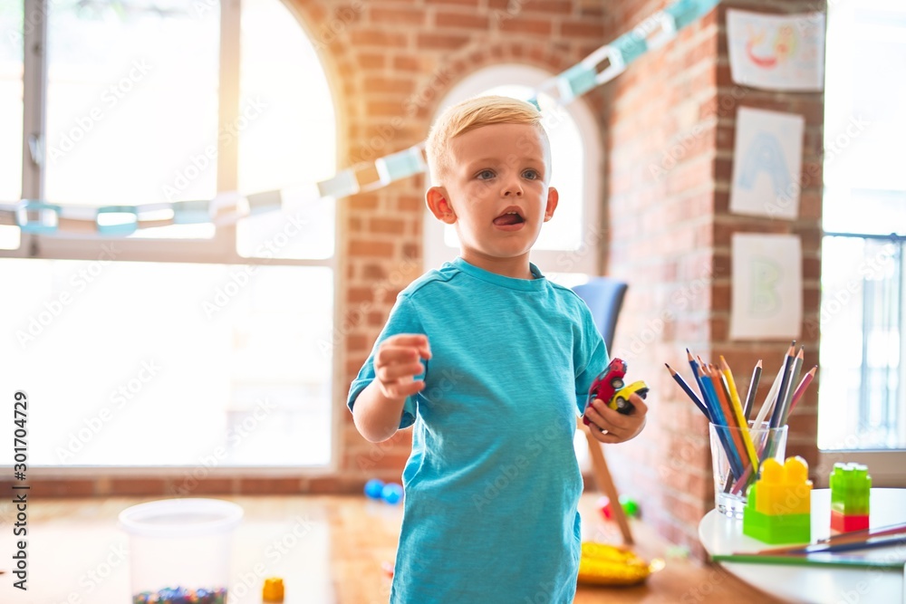 Young caucasian kid playing at kindergarten with toys. Preschooler boy happy at playroom. Young caucasian kid playing at kindergarten with toys. Preschooler boy happy at playroom.