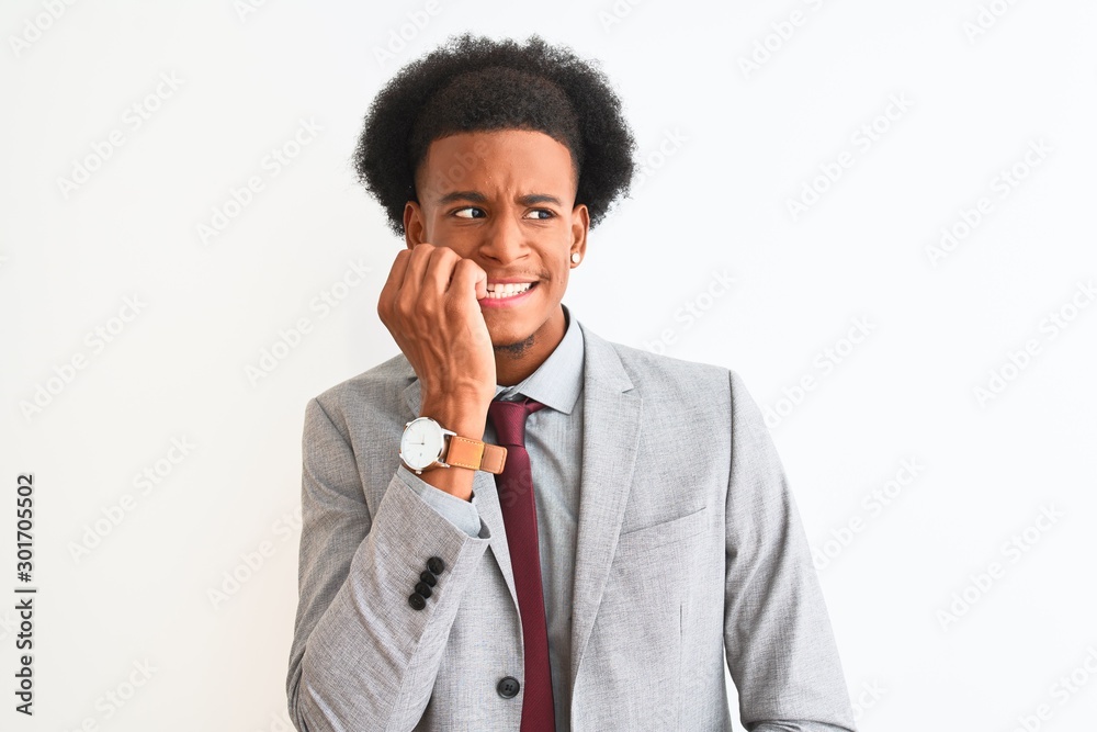 Young african american businessman wearing suit standing over isolated white background looking stressed and nervous with hands on mouth biting nails. Anxiety problem. Young african american businessman wearing suit standing over isolated white background looking stressed and nervous with hands on mouth biting nails. Anxiety problem.