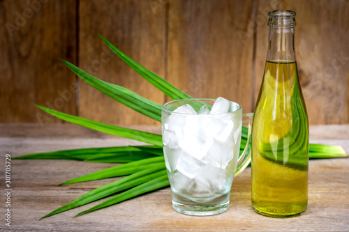 Bottle of water pandan juice and glass of ice with green pandan leaf isolated on rustic wood table background. Natural herbal plant, fragrant screw pine and healthy drinks concept. Vintage style. photo