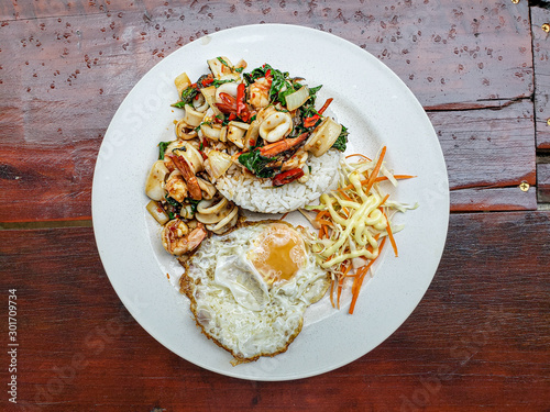Stir fries seafood with chilis and Thai hot basil served with salad and mayonnaise dressing (Thai street food : Pad Kra Praow Talay)