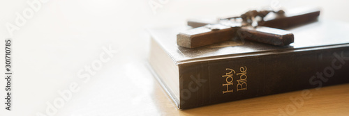 Closeup of wooden Christian cross on Bible, vintage tone. Symbol of God and goodness.