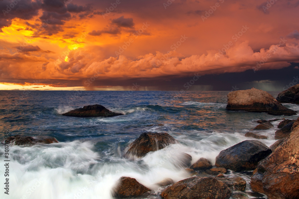 Sunset on the rocky shore of tropical sea