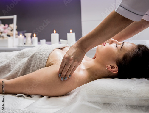 Beautiful young woman enjoying massage in spa salon. Cosmetology