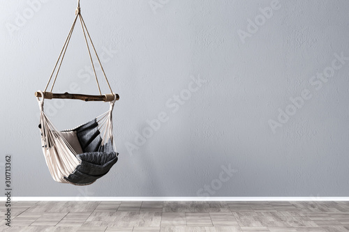 Swing chair in front of gray mockup wall, 3D Rendering, 3D Illustration