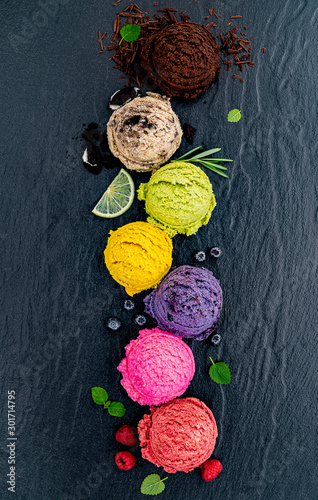 Various of ice cream flavor ball blueberry ,lime ,pistachio ,almond ,orange ,chocolate and vanilla set up on dark stone background . Summer and Sweet menu concept.
