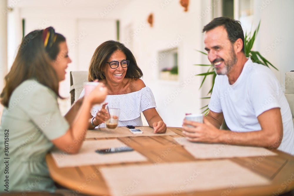 Beautiful family sitting on terrace drinking cup of coffee speaking and smiling