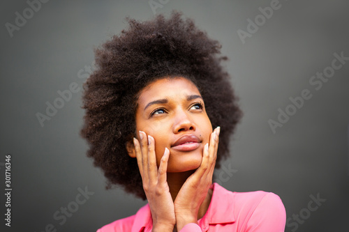 Close up portrait of beauty young african american woman with hands on face against gray wall