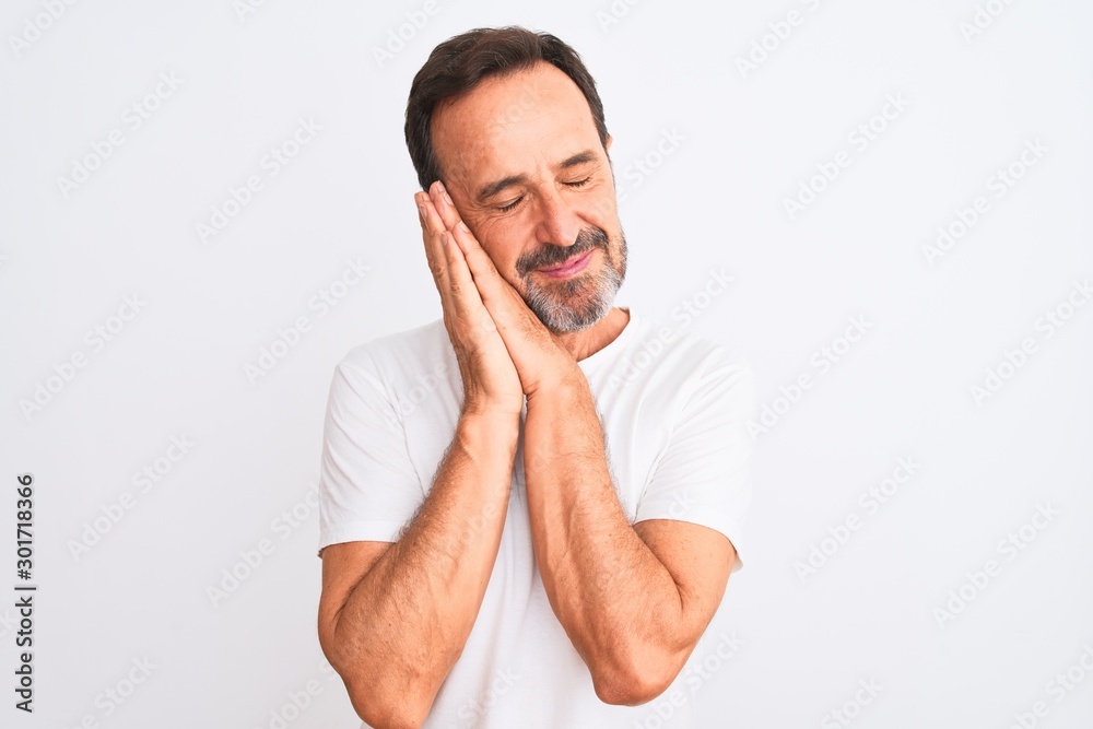 Middle age handsome man wearing casual t-shirt standing over isolated white background sleeping tired dreaming and posing with hands together while smiling with closed eyes. Middle age handsome man wearing casual t-shirt standing over isolated white background sleeping tired dreaming and posing with hands together while smiling with closed eyes.