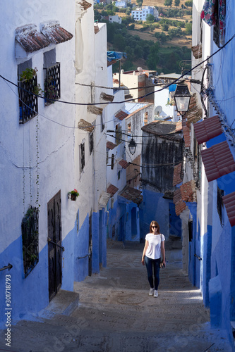 Woman travels through the narrow blue streets of the old Medina in Chefchaouen town in Morocco.  © vadim_ozz