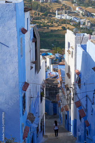 Girl travels through the narrow blue streets of the old Medina in Chefchaouen town in Morocco.  © vadim_ozz