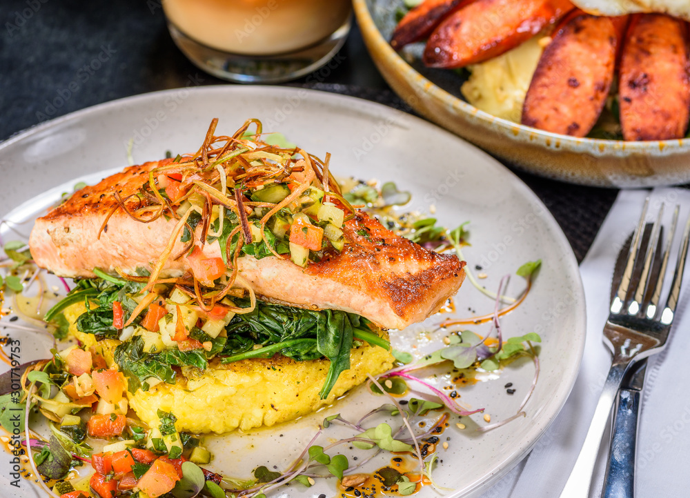 A serving of Grilled Salmon with Saffron Risotto and Vierge Salsa