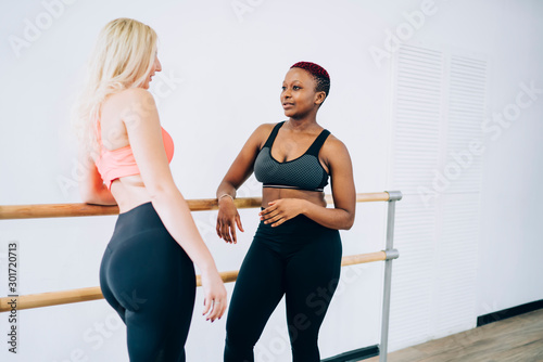 Multiethnic sportswomen friendly chatting in exercise room