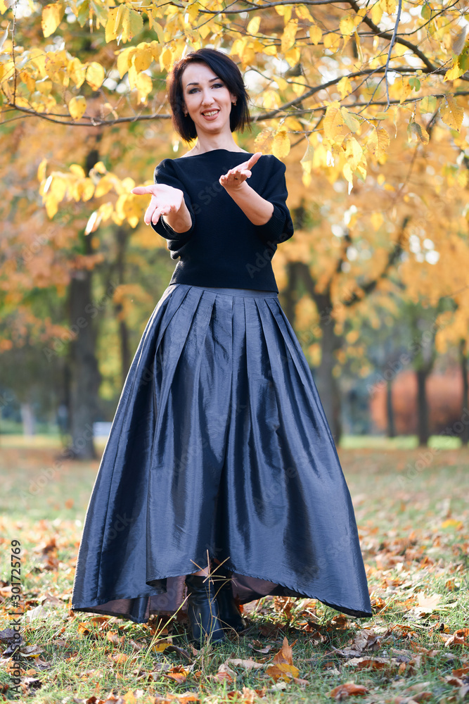 Beautiful elegant woman standing and posing in a city park in autumn Beautiful elegant woman standing and posing in a city park in autumn