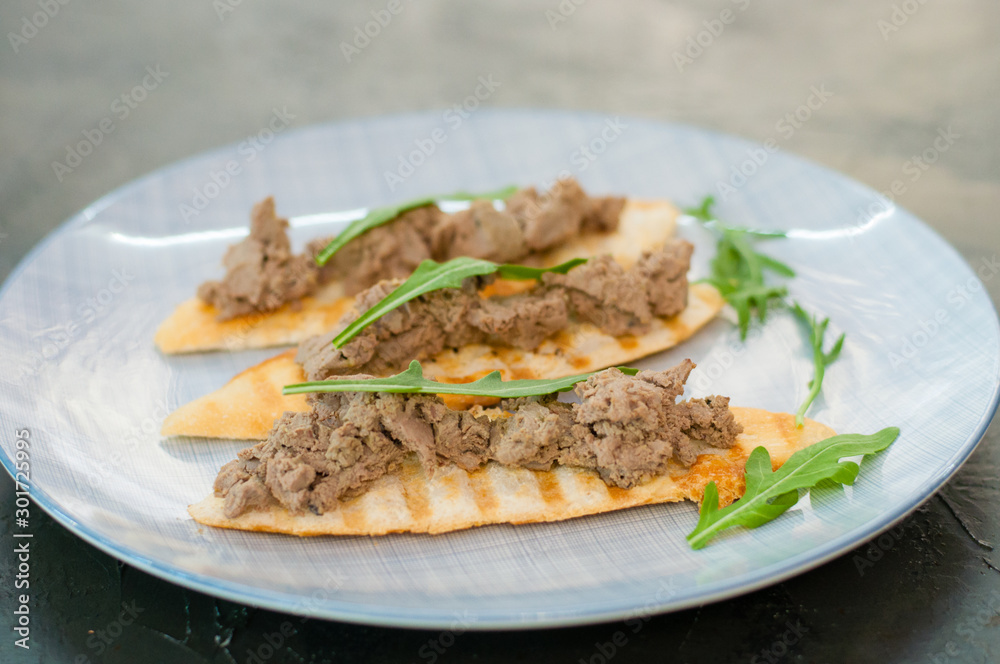 Toasts with pate and arugula. Festive appetizer, New Year's Italian dish. The view from the side and there is room for text Toasts with pate and arugula. Festive appetizer, New Year's Italian dish. The view from the side and there is room for text