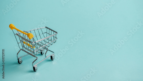 Shopping cart on blue background. Supermarket shop trolley as sale, discount, shopaholism concept with copy space for text or design.