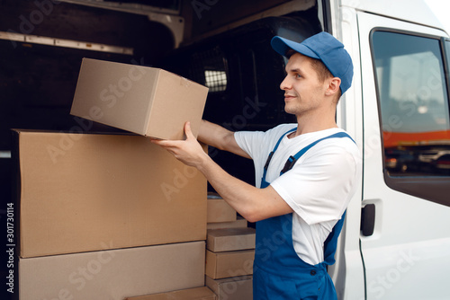 Smiling deliveryman with carton box at the car photo