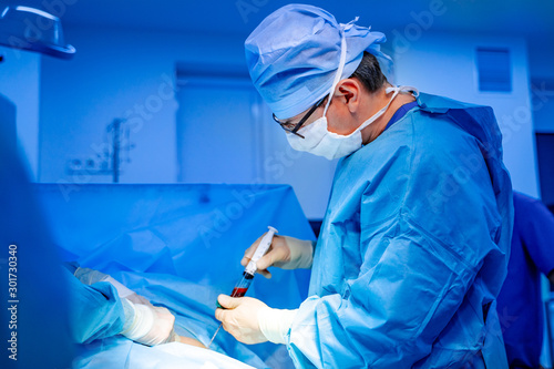 Stem cells operation. Health care concept. Surgeons team working. Bone marrow transplant operation. Plasma in syringe. Selective focus. Medical room background. photo