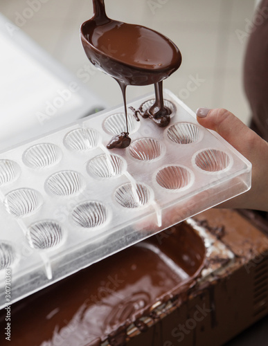 Production of chocolate, pouring melted chocolate mass into molds, chocolate factory
