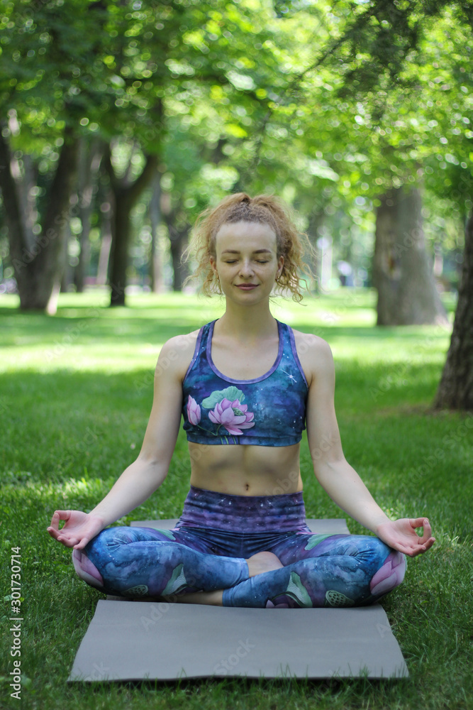 Girl with curly blond hair doing yoga outdoors in the park.