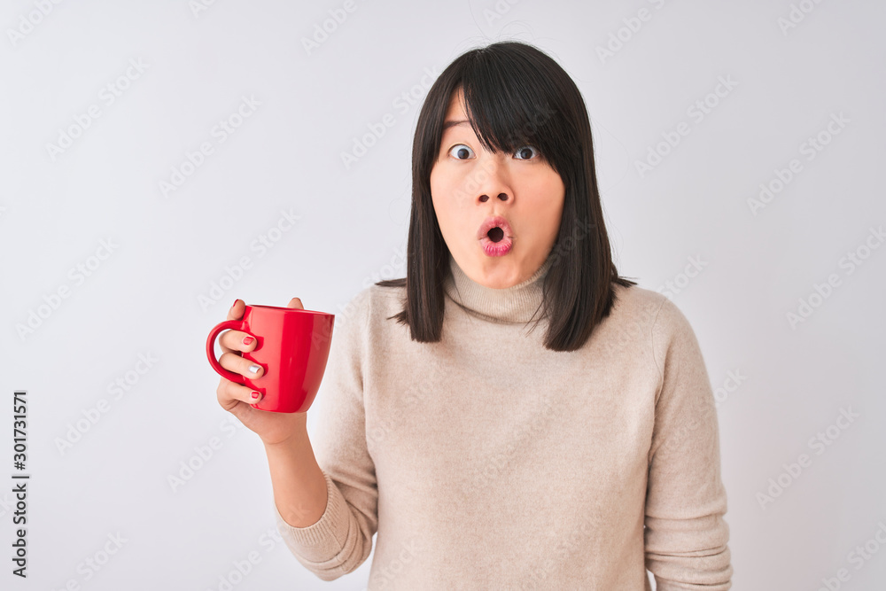 Young beautiful Chinese woman drinking red cup of coffee over isolated white background scared in shock with a surprise face, afraid and excited with fear expression Young beautiful Chinese woman drinking red cup of coffee over isolated white background scared in shock with a surprise face, afraid and excited with fear expression