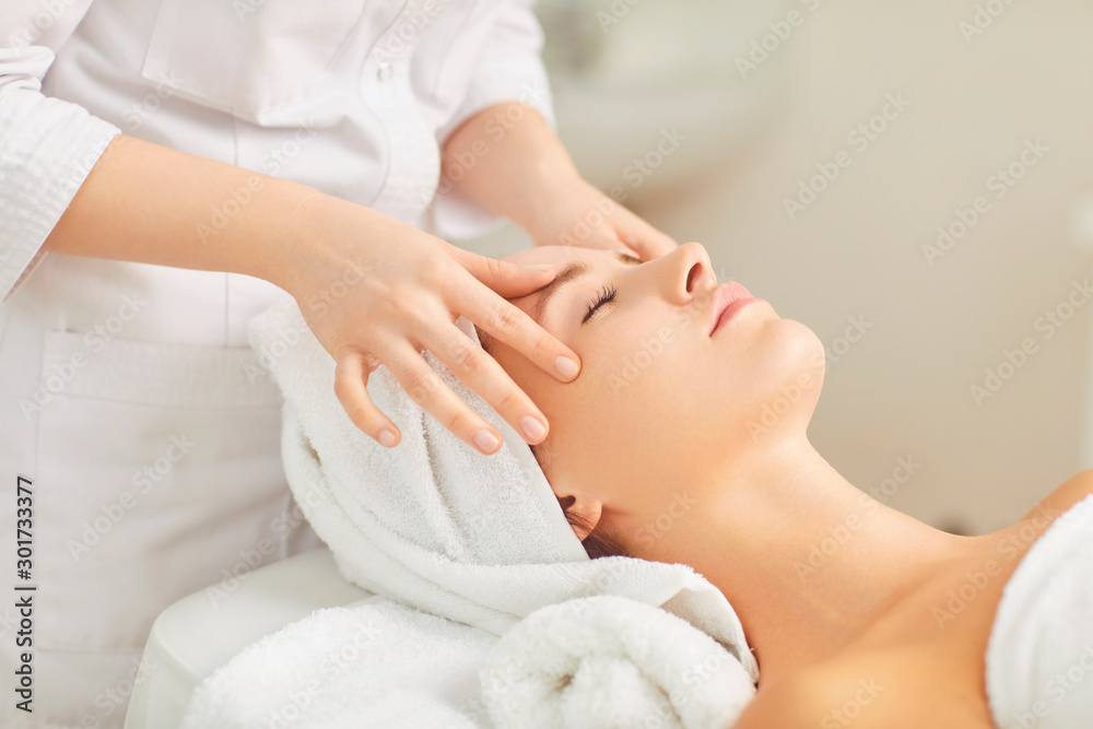 Beautician makes facial massage to the girl Beautician makes facial massage to the girl