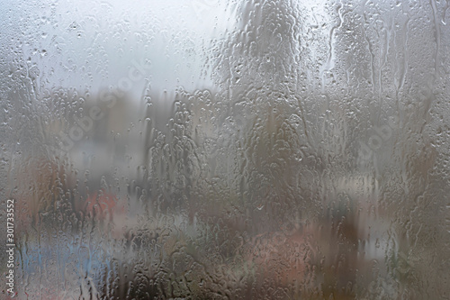 Drops of water on a window pane against a foggy cityscape