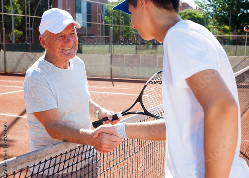 mature senior and young man shake hands before tennis match © caftor
