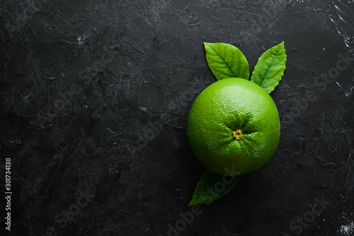 Sweetie green citrus fruit. On a black stone background. Top view. Free copy space. photo