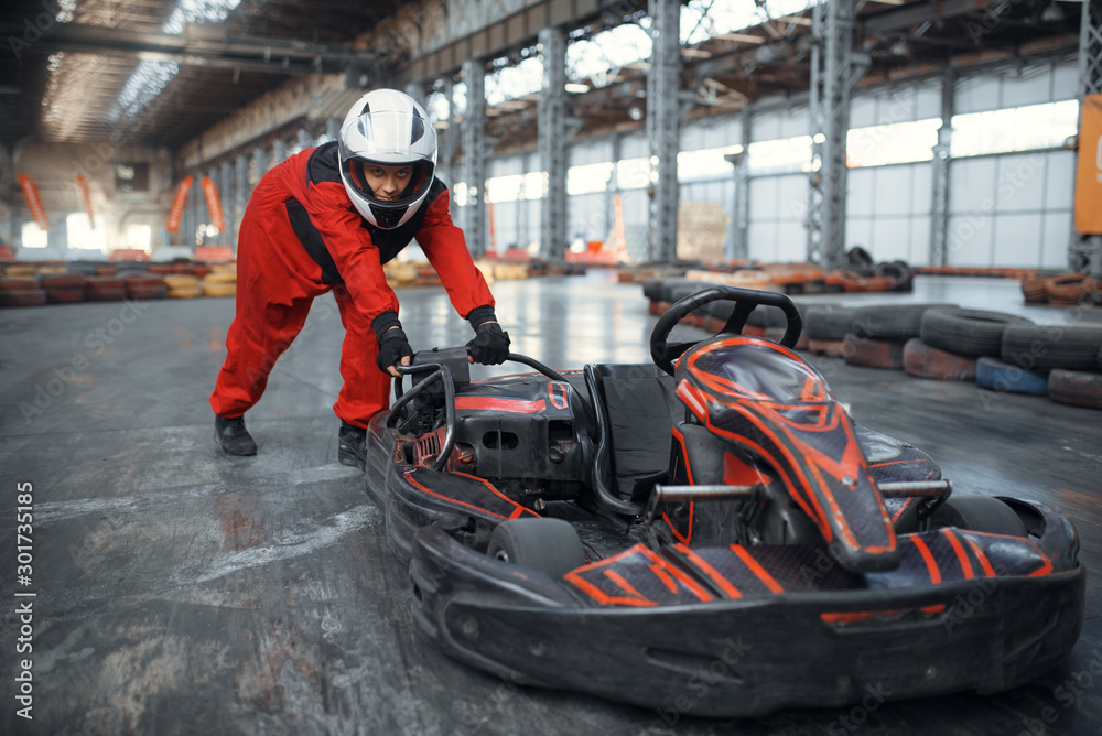 Fototapeta premium Racer in helmet pushing a go kart car, karting