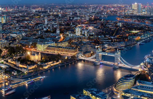 Blick auf die beleuchtete Skyline von London am Abend mit Tower Bridge und modernen Bürogebäuden entlang der Themse