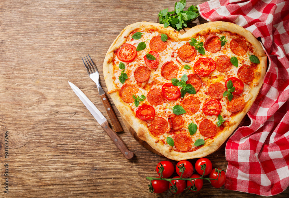 Valentines Day food. Heart shapped pepperoni pizza with green basil,  top view
