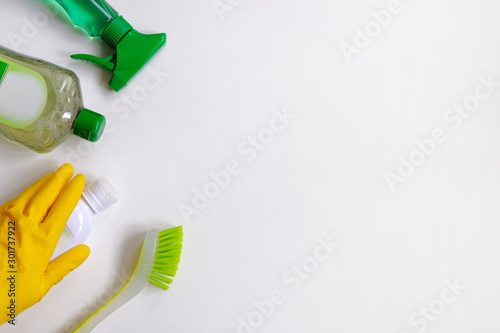 Collection of green and white cleaning supplies on white background. Detergents in plastic bottles. Flat lay. Close up.