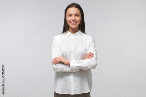European lady standing with arms crossed, showing she is ready to guide and support, isolated on gray background