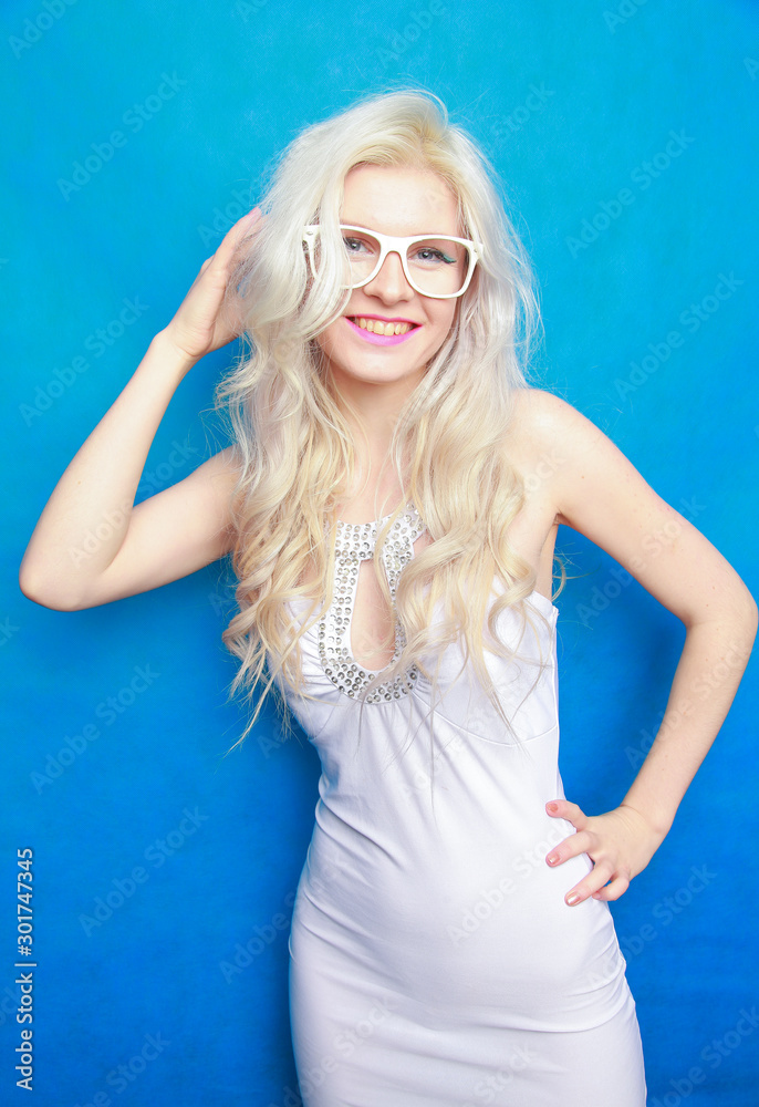 Cute young slender blonde woman with white glasses on blue studio background Cute young slender blonde woman with white glasses on blue studio background
