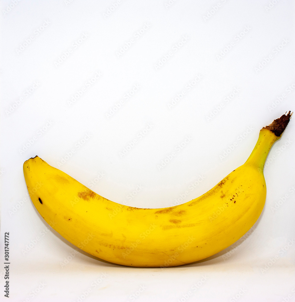 One natural banana with dark spots on a white background close-up. Organic fruits.