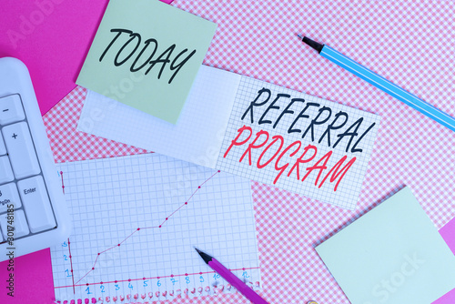 Writing note showing Referral Program. Business concept for employees are rewarded for introducing suitable recruits Writing equipments and computer stuffs placed above colored plain table
