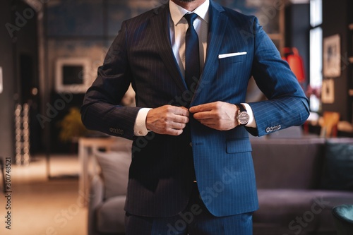 Handsome man adjusting his jacket while standing in modern office. photo