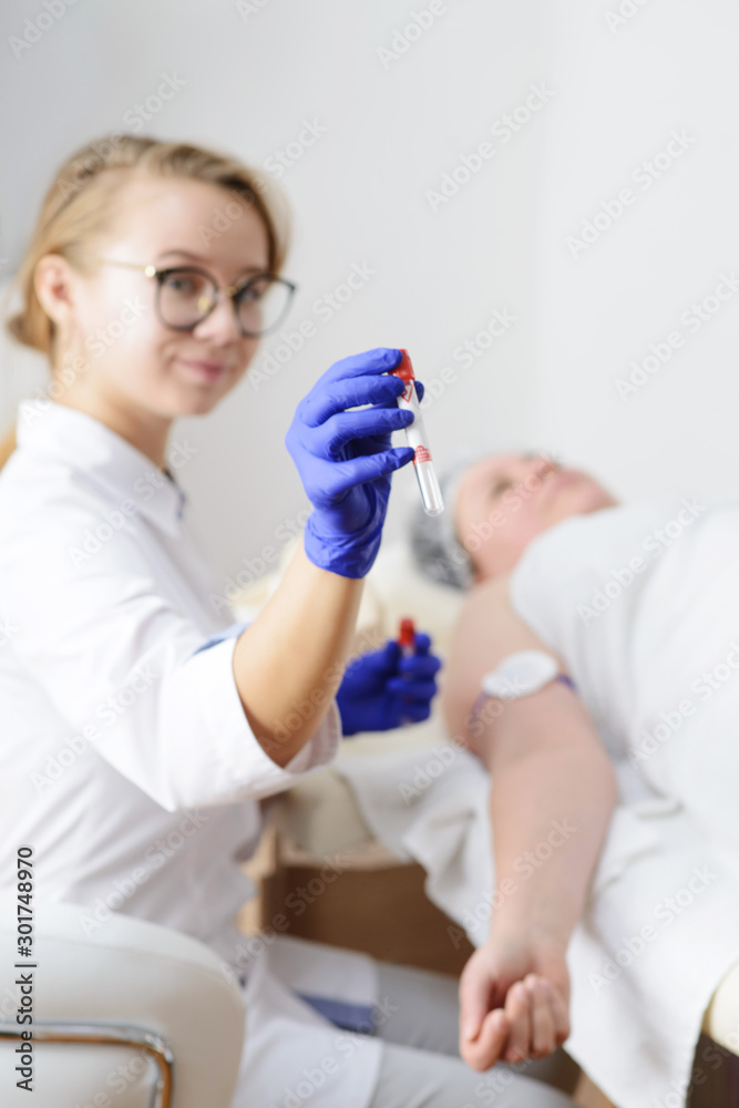 Smiling doctor in latex gloves holding test tube . Blood test from the vein of the hand Smiling doctor in latex gloves holding test tube . Blood test from the vein of the hand