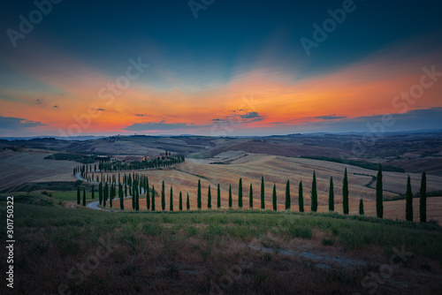 Wonderful sunset over Tuscany hills with alley of cypress trees. Travel destination Tuscany, Italy