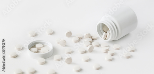 Scattered white pills from a jar. Isolated on white background.